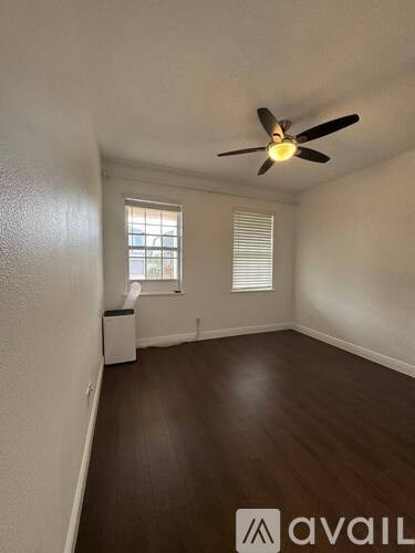 A room with a ceiling fan and wooden flooring.