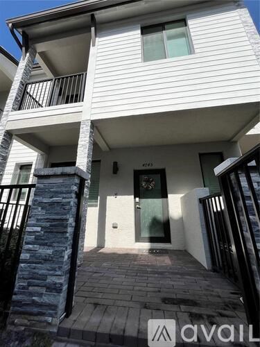 A white two-story house with a balcony and a stone pillar.