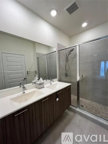 A bathroom with a sink, mirror, and shower.