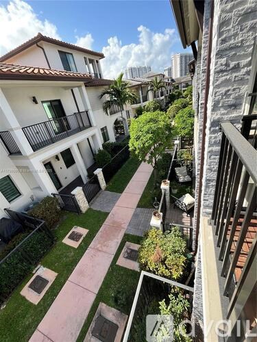 A balcony overlooks a small garden with a pink walkway.