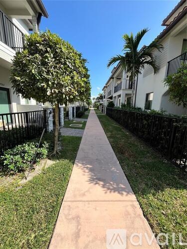 A sidewalk runs down the middle of a grassy area between two rows of houses.