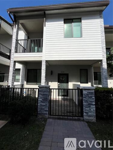 A white two-story apartment building with a black gate in front.