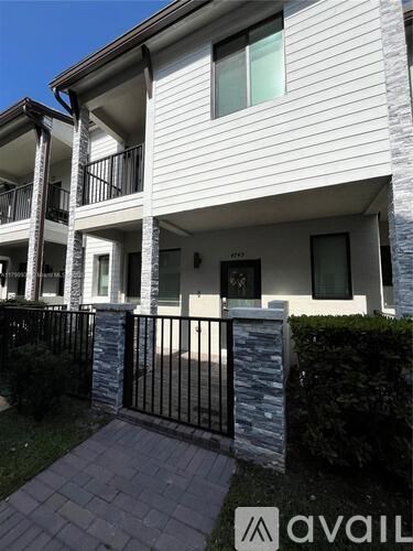 A white two-story building with a black gate in front.