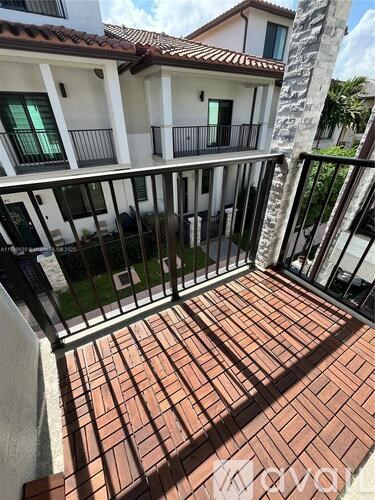 A balcony with a brick floor and a metal railing.