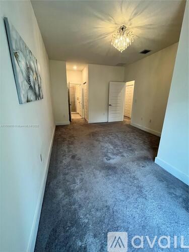 A spacious room with a chandelier and a painting on the wall.