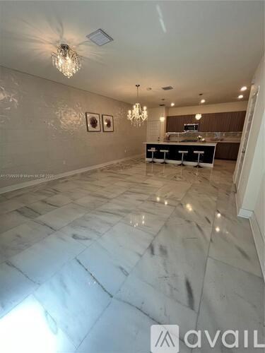 A spacious room with marble flooring and a chandelier.