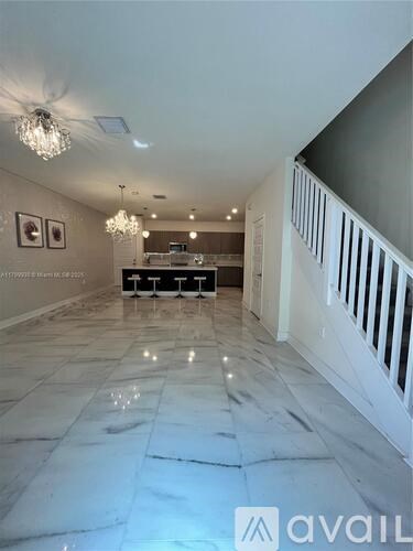 A spacious room with marble flooring and a chandelier.