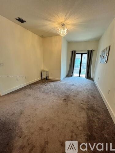 A room with a carpeted floor and a chandelier hanging from the ceiling.