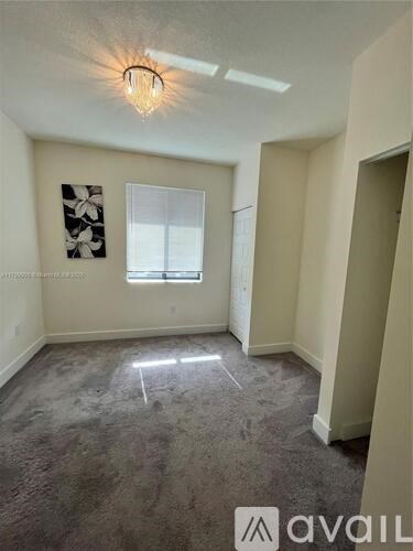 A room with a carpeted floor and a window with blinds.