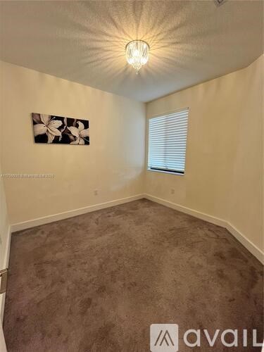 A room with a carpeted floor and a painting on the wall.