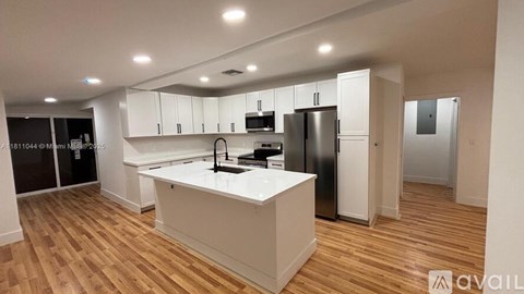 A kitchen with white cabinets and a wooden floor.