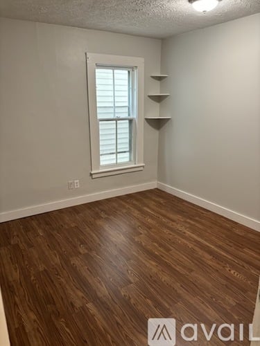 A room with wooden flooring and a window with shutters.