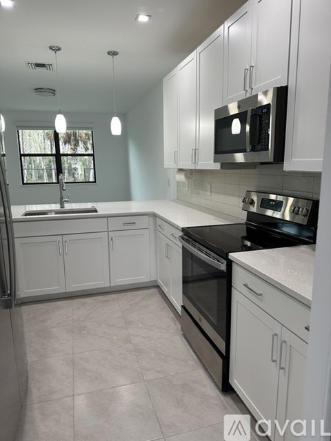 A kitchen with white cabinets and appliances.