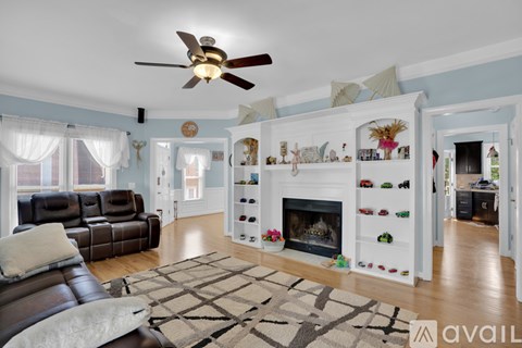 A living room with a brown leather couch and a fireplace with white mantle.