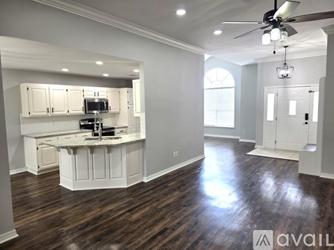 A spacious kitchen with white cabinets and a wooden floor.