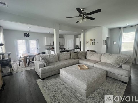 A spacious living room with a grey sofa set and a wooden floor.