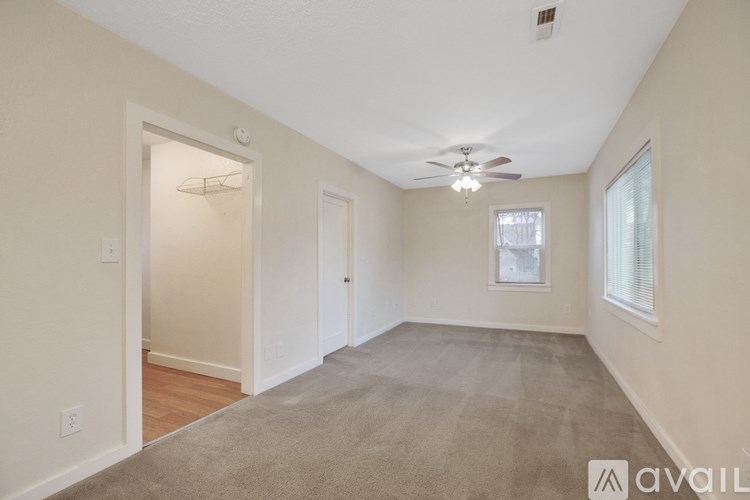 A spacious room with a carpeted floor and a ceiling fan.