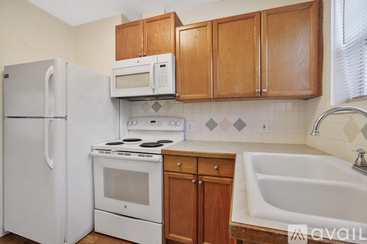 A kitchen with white appliances and wooden cabinets.