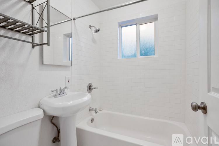 A white bathroom with a sink, bathtub, and a window.