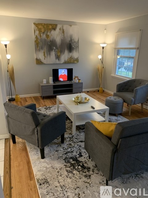A living room with a grey couch, a white coffee table, and a painting on the wall.