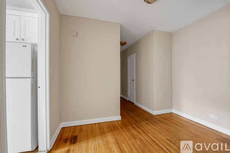 A room with wooden floors and a white refrigerator.