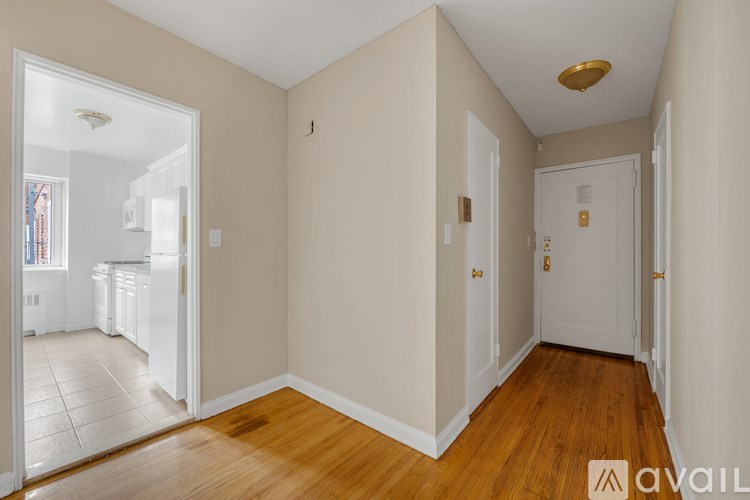 A room with wooden floors and white walls, with a door on the right and a window on the left.