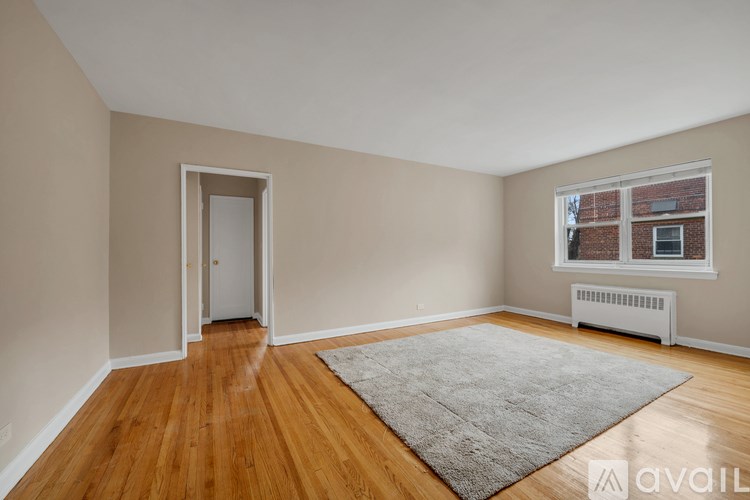 A room with wooden floors and a window with a view of a brick building.