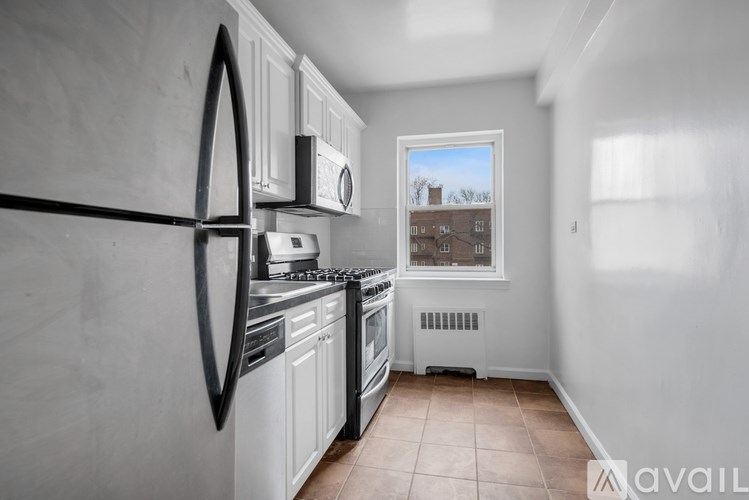 A kitchen with white appliances and a window showing a building outside.