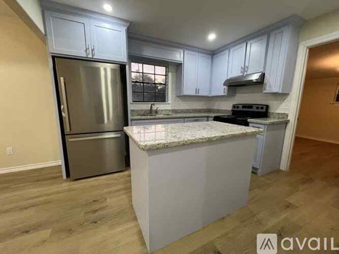 A kitchen with a stainless steel refrigerator and a marble countertop.