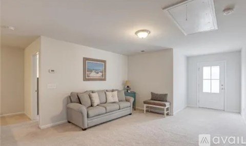 A living room with a grey couch and a painting on the wall.