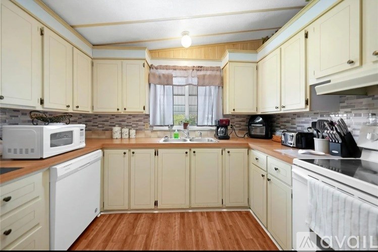 A kitchen with wooden floors and white appliances.