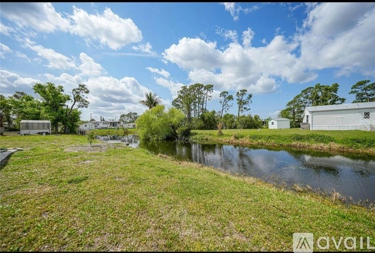 A grassy area with a pond and buildings in the distance.