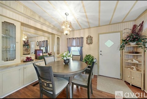 A dining room with a table set for two and a chandelier hanging from the ceiling.