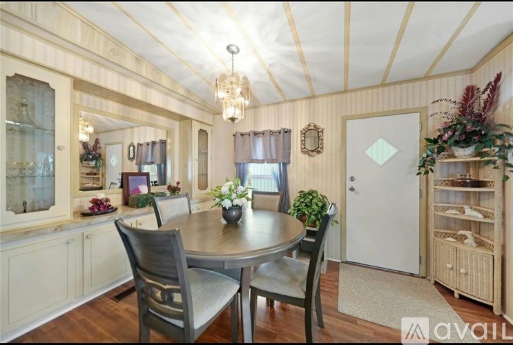 A dining room with a table set for two and a chandelier hanging from the ceiling.