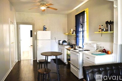 A kitchen with white appliances and a black counter.