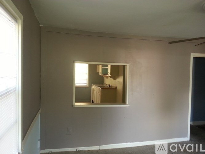 A room with a window and a mirror on the wall.