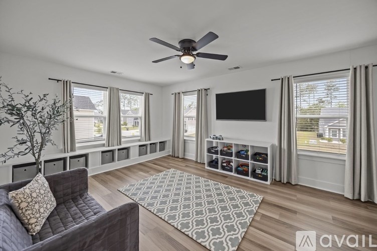 A living room with a grey couch and a ceiling fan.