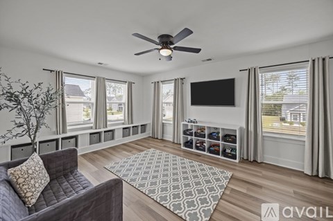 A living room with a grey couch and a ceiling fan.