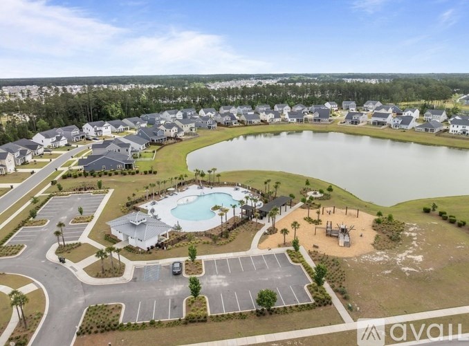 A bird's eye view of a housing complex with a swimming pool and a lake.