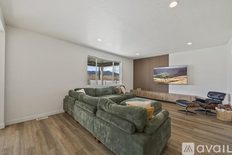 A living room with a green couch and a television on the wall.