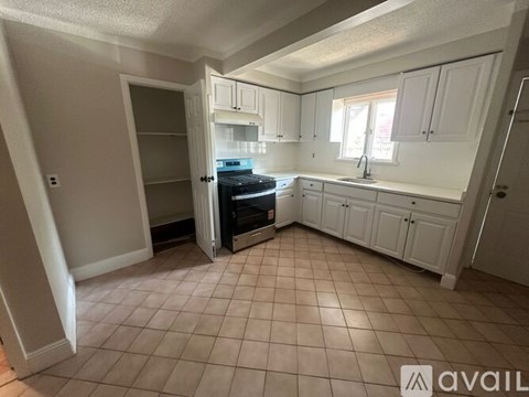 A kitchen with white cabinets and a tiled floor.