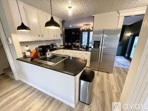 A kitchen with a black countertop and stainless steel appliances.