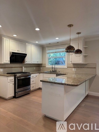 A kitchen with white cabinets and a granite countertop.