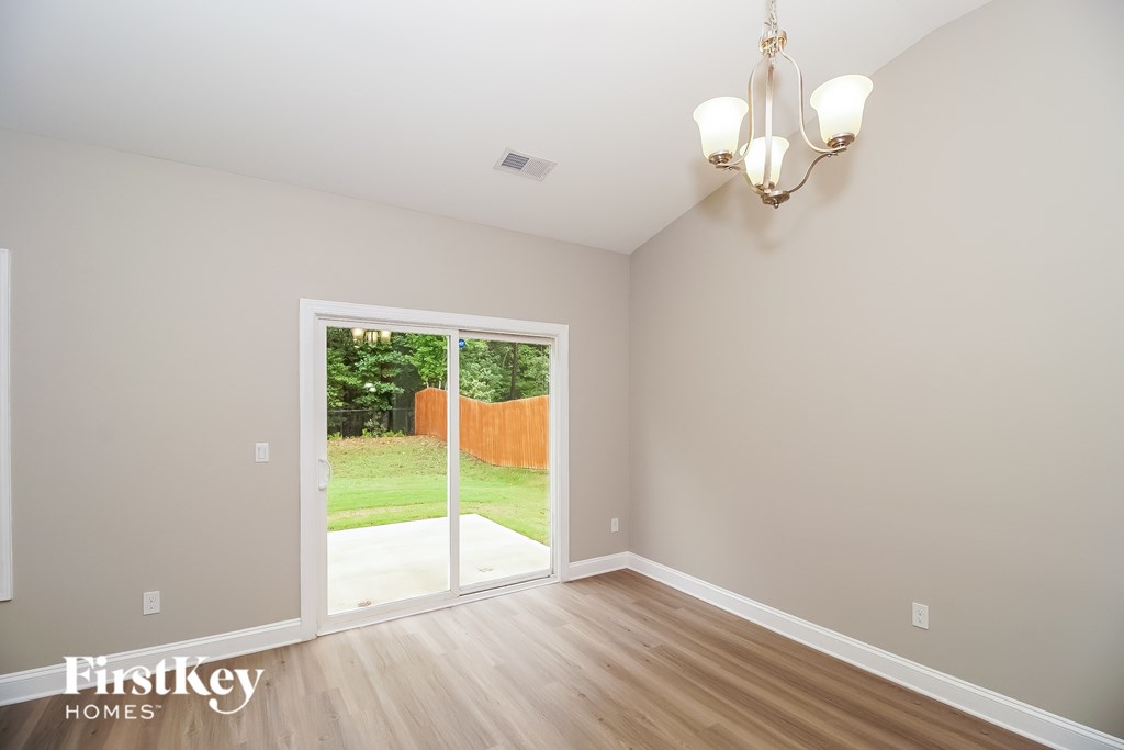 A room with a chandelier and a sliding glass door leading to a backyard.