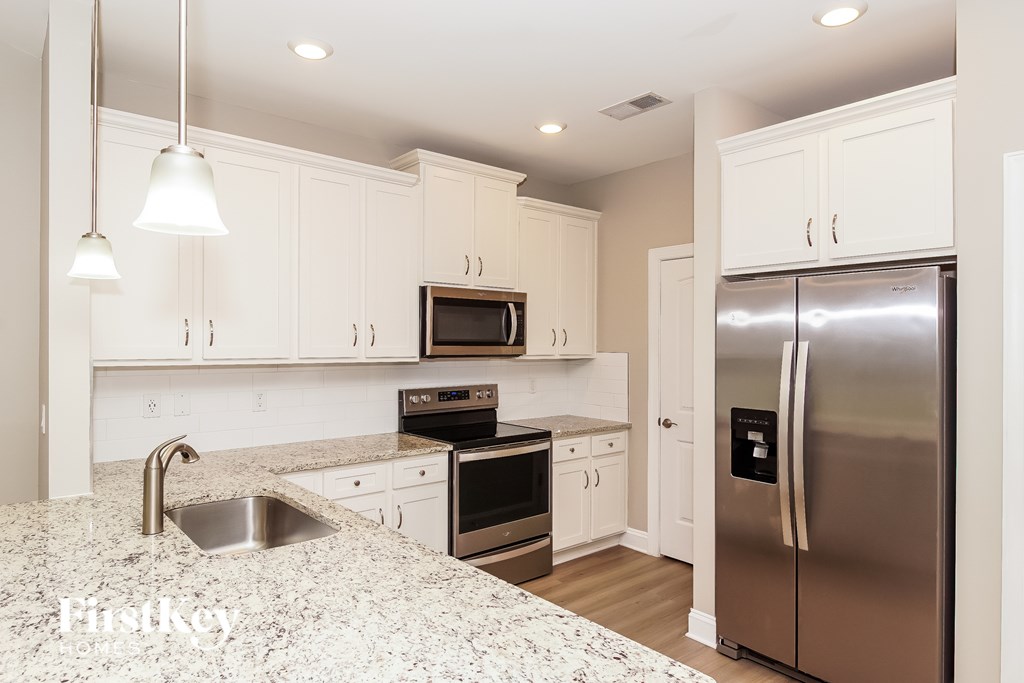 A kitchen with a stainless steel refrigerator and a granite countertop.