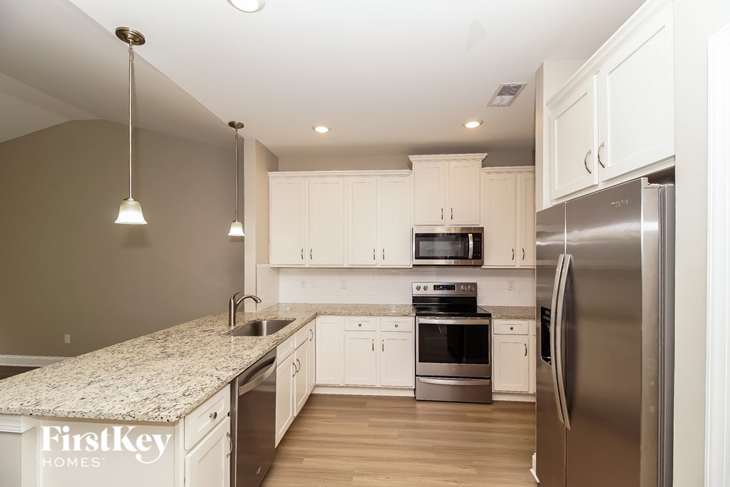 A kitchen with a granite countertop and stainless steel appliances.