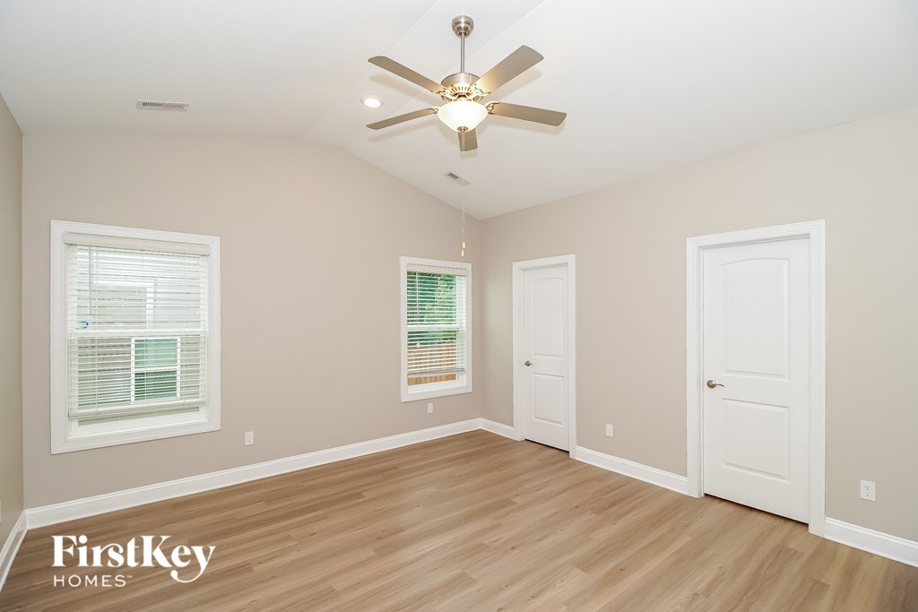 A room with a ceiling fan and three doors.