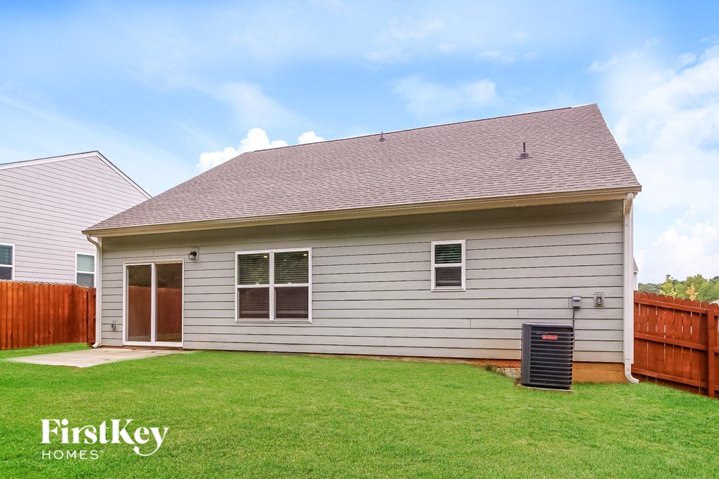 A house with a grey siding and a brown roof with a brown fence and a green lawn.