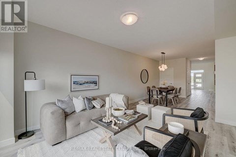 A well-lit living room with a grey sofa, a coffee table, and a dining table with chairs.