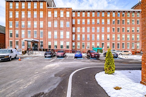 A parking lot in front of a red brick building.